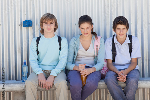 Photo: Three children sitting side by side on bench Three children sitting side by side on bench