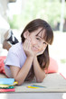 Smiling girl lying outdoors with books and color pencils