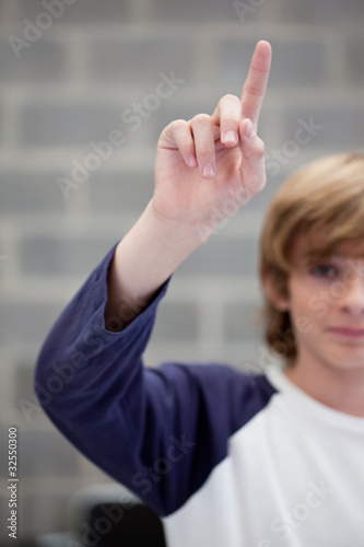 Foto: Schoolboy in classroom raising his hand Schoolboy in classroom raising his hand