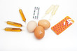 Foto: Organic eggs with feather surrounded by drugs on white Organic eggs with feather surrounded by drugs on white