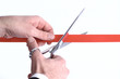 Photo: Closeup of a mans hand cutting a red ribbon with scissors Closeup of a mans hand cutting a red ribbon with scissors