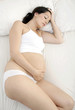 Unhappy pregnant woman laying in bed