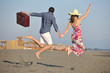 couple on beach with travel bag