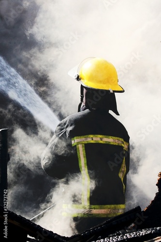 Photo: Fireman Putting out a House Fire Fireman Putting out a House Fire