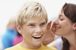 Closeup of a smiling boy being told a secret by a friend