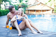 Mature couple with tablet computer and drinks by the poolside