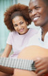 Foto: Portrait of a smiling young couple playing a guitar Portrait of a smiling young couple playing a guitar