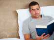 Relaxed young man reading novel at home
