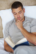 Handsome young guy reading book at home