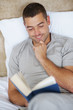 Smart young man reading novel at home