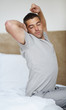 Young guy stretching in morning on bed