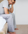 Sleepy young man sitting on bed at home