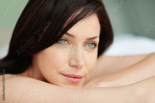 Photo: Elegant young female lying on bed in thought Elegant young female lying on bed in thought