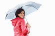Happy young woman in raincoat holding an umbrella