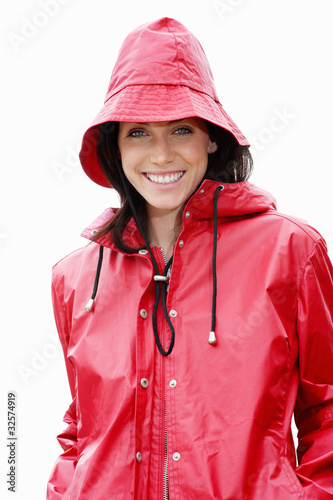 Photo: Cute young woman in red raincoat against white background Cute young woman in red raincoat against white background