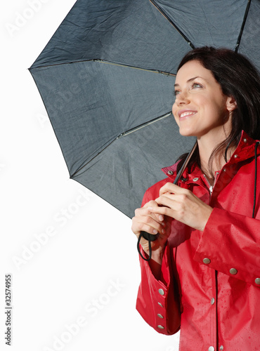 Photo: Smiling young female in red coat holding an umbrella Smiling young female in red coat holding an umbrella