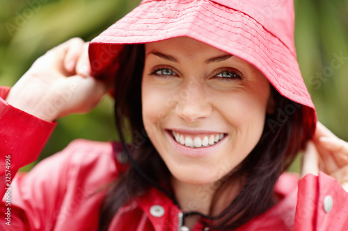 Photo: Smiling cute woman in red raincoat outdoors Smiling cute woman in red raincoat outdoors