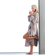 Young blond woman drinking coffee in bathrobe