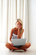 Cheerful young woman using laptop at home