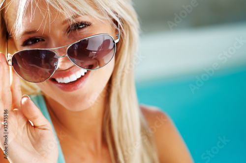 Photo: Happy young woman looking through sun glasses Happy young woman looking through sun glasses