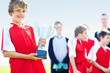 Cute boy holding trophy with blurred team in the background