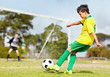 Sporty young boy kicking football towards the goal