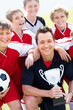 Smiling soccer team with happy coach holding trophy