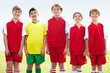Cheerful rival stands amid smiling soccer team in red