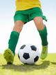 Foto: Low section of a little football player kicking ball on grass Low section of a little football player kicking ball on grass