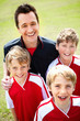 Happy football coach with confident team smiling on field
