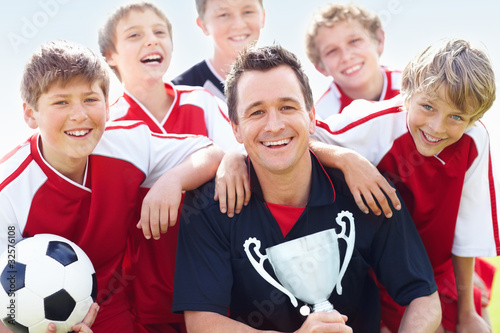 Photo: Successful soccer team with coach holding trophy Successful soccer team with coach holding trophy
