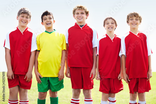 Photo: Cheerful rival stands amid smiling soccer team in red Cheerful rival stands amid smiling soccer team in red
