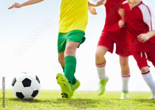 Photo: Low angle shot of players kicking football on field Low angle shot of players kicking football on field