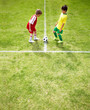 Rival kid players with a ball on soccer field