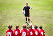 Rear view of player discussing with coach on soccer field