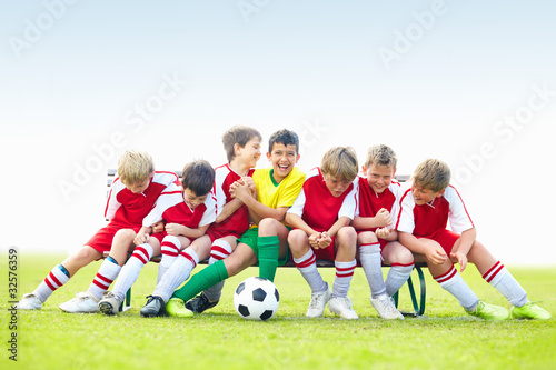 Foto: Mischievous soccer kids having fun on bench - copyspace Mischievous soccer kids having fun on bench - copyspace