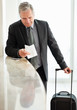 Photo: Senior man with his luggage, reading a receipt at check in Senior man with his luggage, reading a receipt at check in