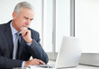 Thoughtful senior business man working on laptop at office