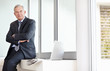 Business man with hands folded and laptop in background