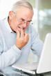 Thoughtful mature man looking at laptop