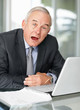 Sleepy business man at a table with laptop trying to keep awake