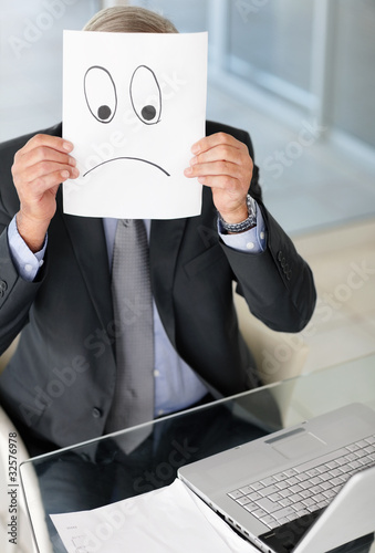 Foto: Mature man holding a sad sign on sheet of paper over his face Mature man holding a sad sign on sheet of paper over his face