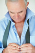 Mature business man buttoning his shirt