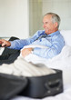 Mature business man with a remote control watching television