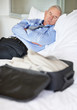 Tired matured business man with luggage sleeping in bed