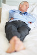 Tired matured business man lying in bed at hotel