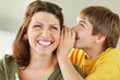 Happy young boy sharing a secret with his mother