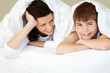 Happy boy and his mother under blanket at home