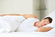 An attractive young man sleeping in bed at home