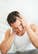 Young man suffering from a severe headache holds his head